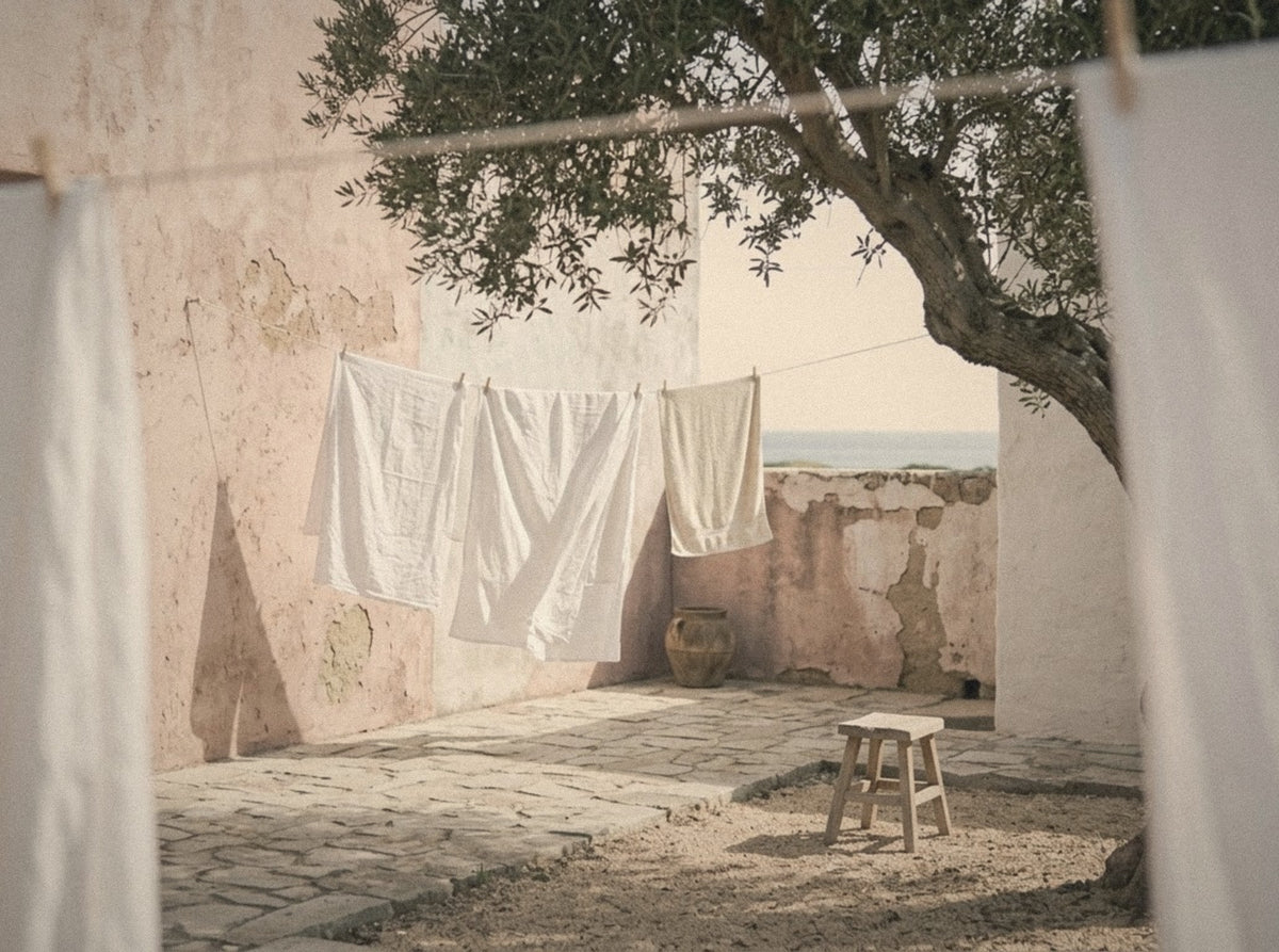 Courtyard with white linen drying on a line under an olive tree
