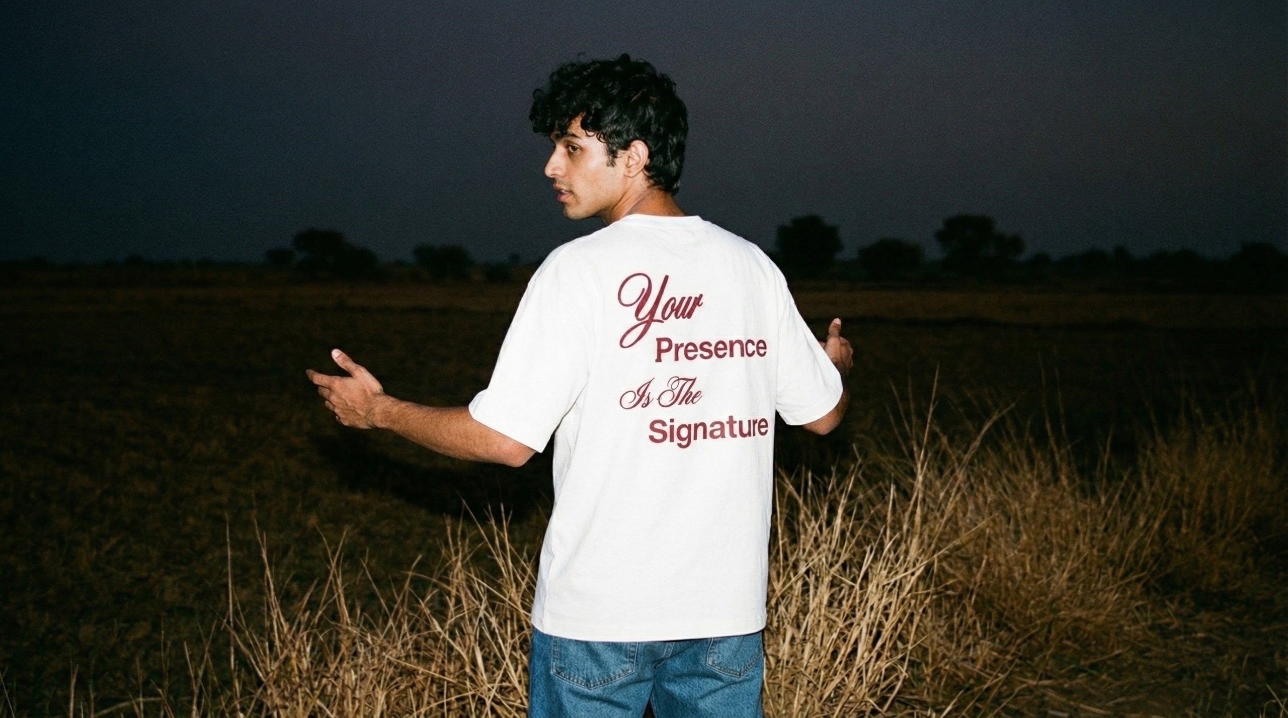 Model wearing Hallberd The Mark t-shirt 
walking away through haveli archway at night, 
flash candid photography India